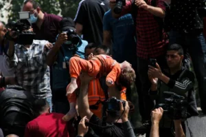 A Palestinian man holds a child who was rescued from the rubble of destroyed houses